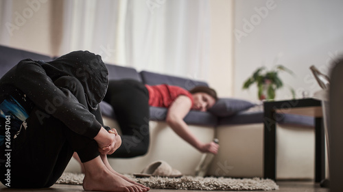 mother of an alcoholic in an unconscious state passed out with a bottle in her hands. the child is closed from the problem of drunkenness in the family. a helpless child is closed out of desperation.