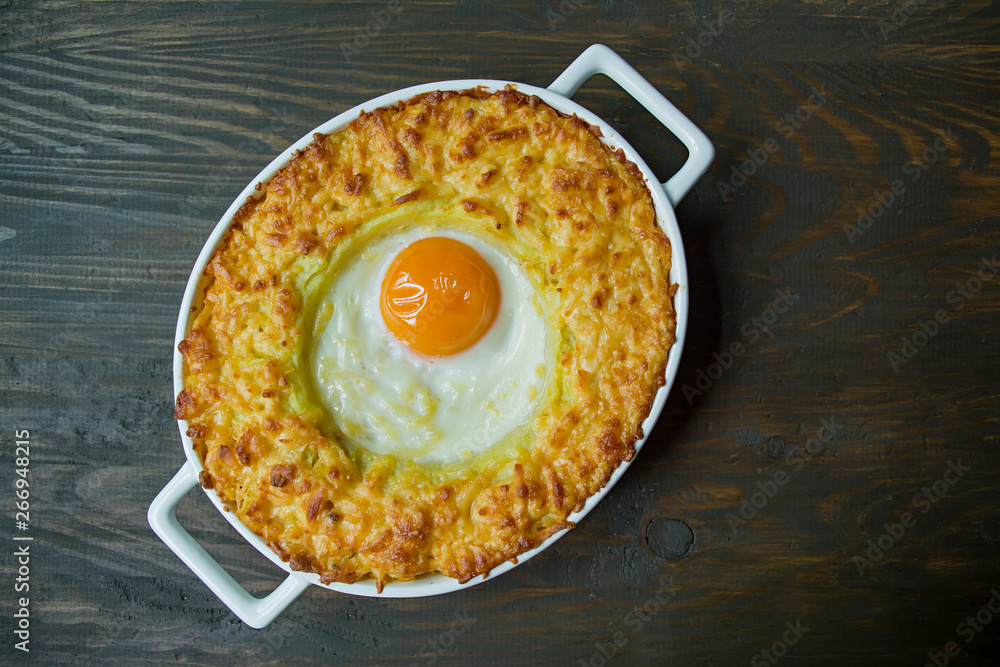 Potato casserole with bolognese. Baked potato casserole with egg and grated cheese in a ceramic oval baking sheet. Wooden dark background. Potato casserole with bolognese. Baked potato casserole with egg and grated cheese in a ceramic oval baking sheet. Wooden dark background.