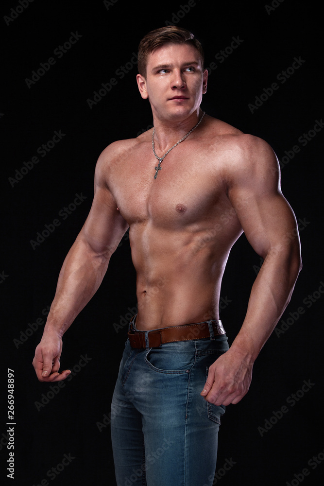 Fototapeta premium Bodybuilding competitions on the scene. Man sportsmen physique and athlete. Black background with lights.