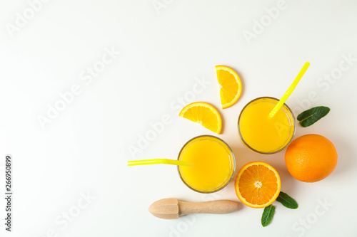 Flat lay composition with fresh orange juices, wooden juicer, mint, oranges and wooden juicer on white background, top view and space for text. Fresh natural drink and fruits