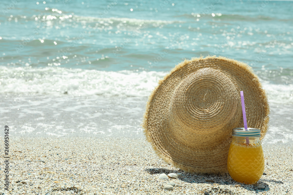 Straw hat and orange juice on seaside, space for text. Summer vacation background Straw hat and orange juice on seaside, space for text. Summer vacation background