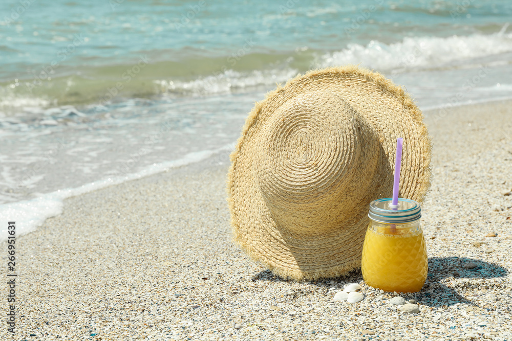 Straw hat and orange juice on seaside, space for text. Summer vacation background Straw hat and orange juice on seaside, space for text. Summer vacation background