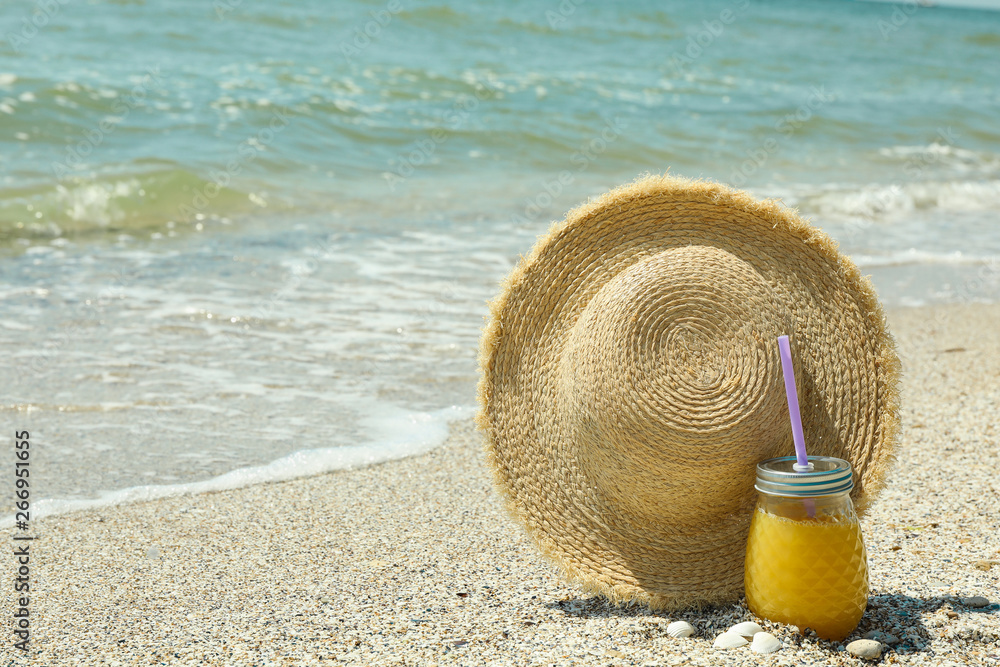Straw hat and orange juice on seaside, space for text. Summer vacation background Straw hat and orange juice on seaside, space for text. Summer vacation background