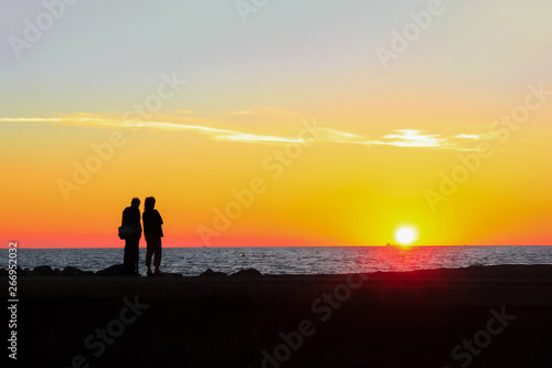 Man and woman admire the colorful sunset on the beach