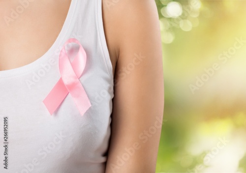 Heart framing from fingers on woman chest with pink badge to support breast cancer cause, PS: you can change the ribbon color to red to support AIDS cause as both using same symbol