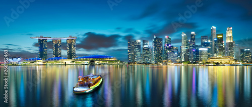Panorama view of Singapore city skyline with tourist boat at night . Travel asia concept .