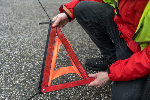 A person builds a warning triangle on the street