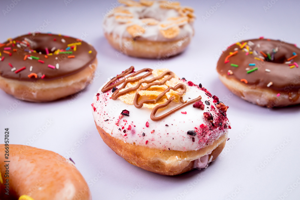 Breakfast of delicious glazed donuts, mix of flavors - purple background Breakfast of delicious glazed donuts, mix of flavors - purple background