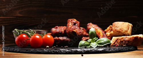 Spicy hot grilled spare ribs from a summer BBQ served with fresh tomatoes on an vintage cutting board