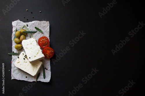 Feta Greek chesse with tomatoes and olives on black background