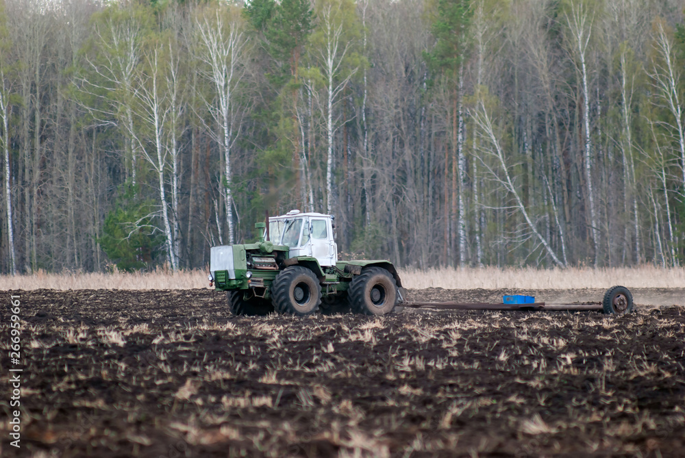 Fototapeta premium The tractor handles the soil. Spring field work.