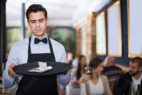 man waiter looking at a tip on a tray