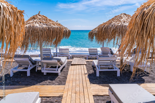 Empty deck chairs and umbrellas on the black sand beach in Perissa  Santorini  Greece