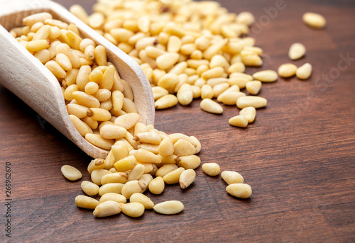 Peeled pine nuts. In wooden spoon. Foreground. Wood background Rustic, natural and homemade appearance.