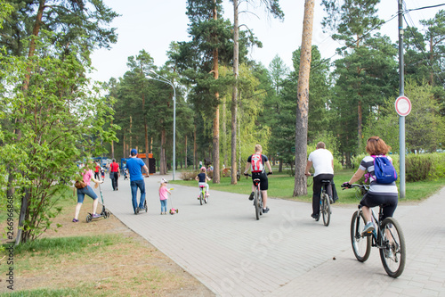 parents with children ride bikes and scooters in the park