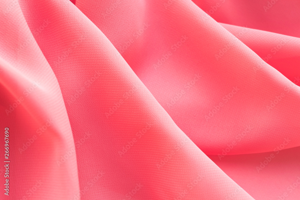 pink silk texture. background of coral fabric lying folds on the table pink silk texture. background of coral fabric lying folds on the table