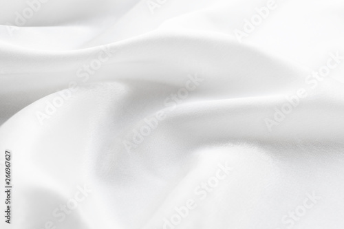white silk texture. background of white fabric lying folds on the table