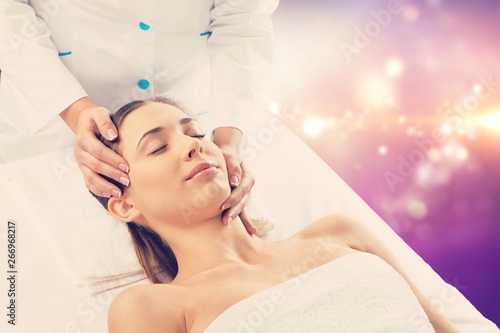 Beautiful young woman enjoying head massage in spa center