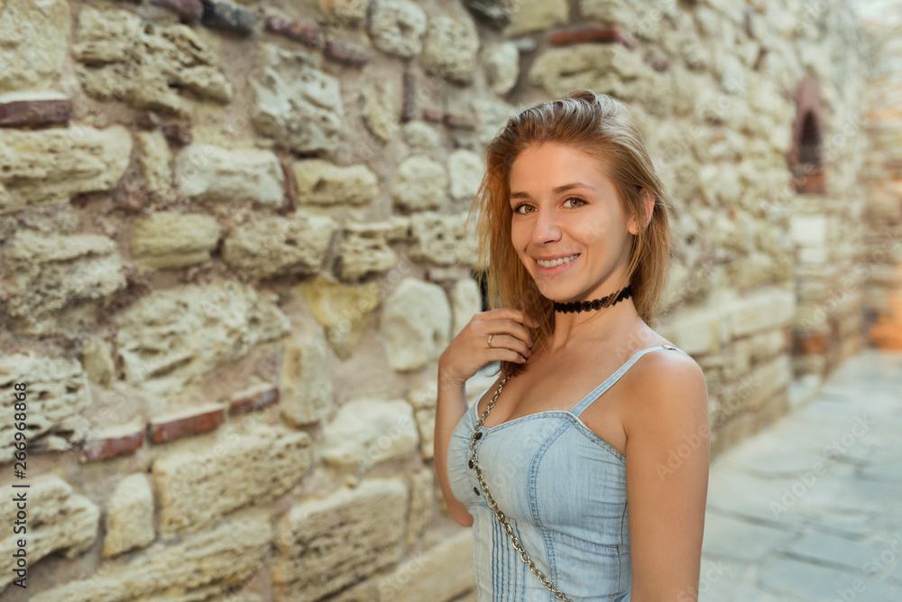 Smiling girl sightseeing monument - ancient town ruins. Stone walls. Warm sunlight of sunset.