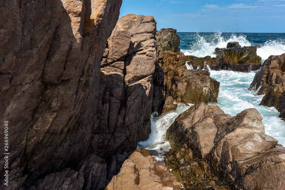 Obraz premium Phenomenal and scenic sea waves crashing against rocky coast. Sunny day during summer vacation. Beautiful force of nature.