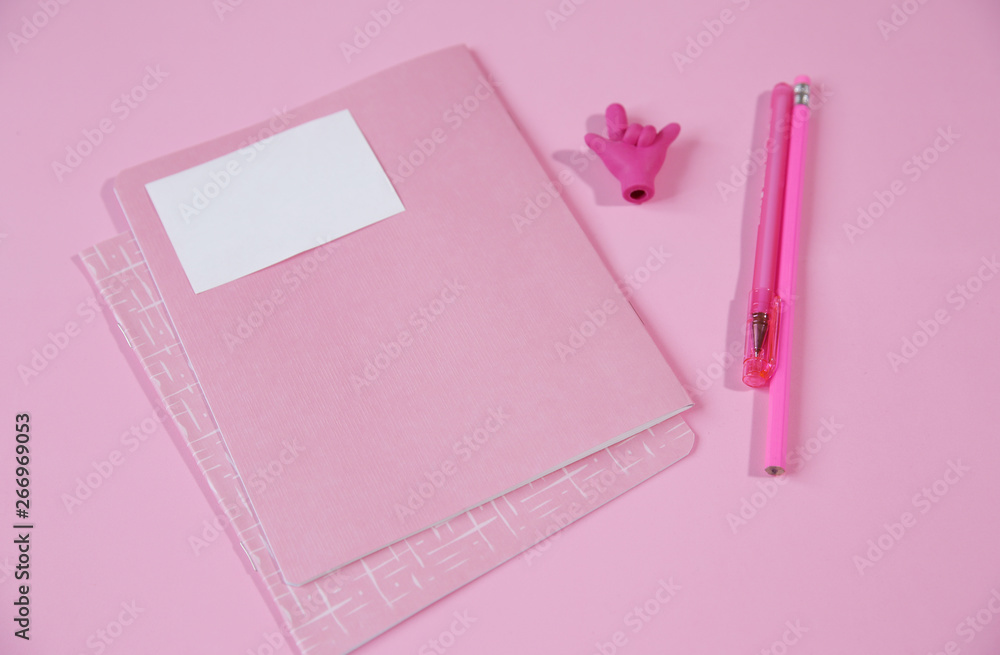 pink notebook and pink pen with a pencil, an eraser in the form of a hand showing a good luck sign on a pink background with copy space for text pink notebook and pink pen with a pencil, an eraser in the form of a hand showing a good luck sign on a pink background with copy space for text