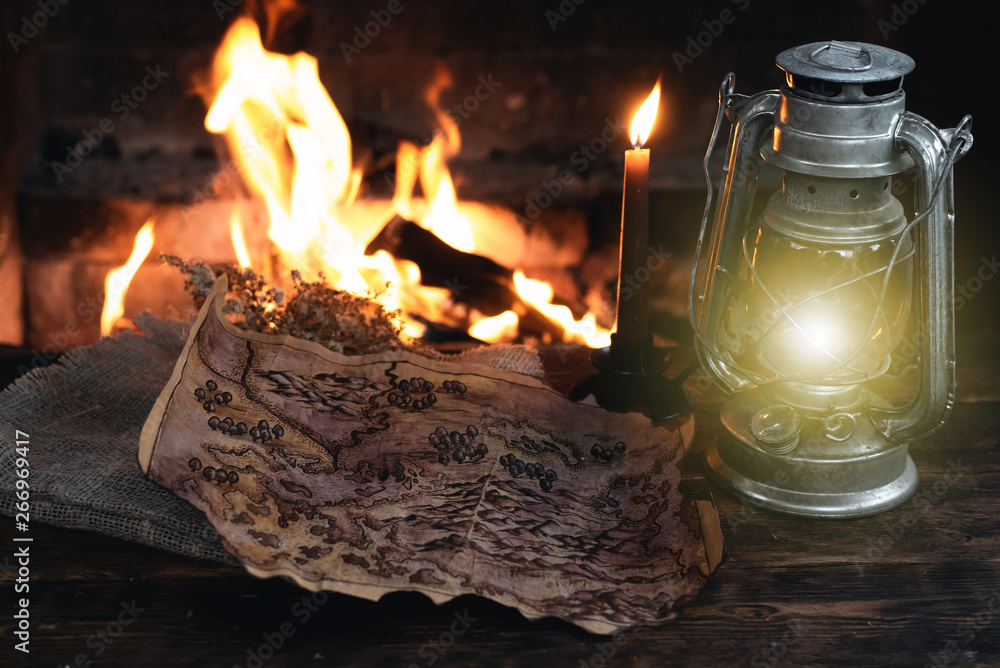 Pirate treasure map and kerosene lamp over a burning fire background. Treasure hunt concept. Pirate treasure map and kerosene lamp over a burning fire background. Treasure hunt concept.
