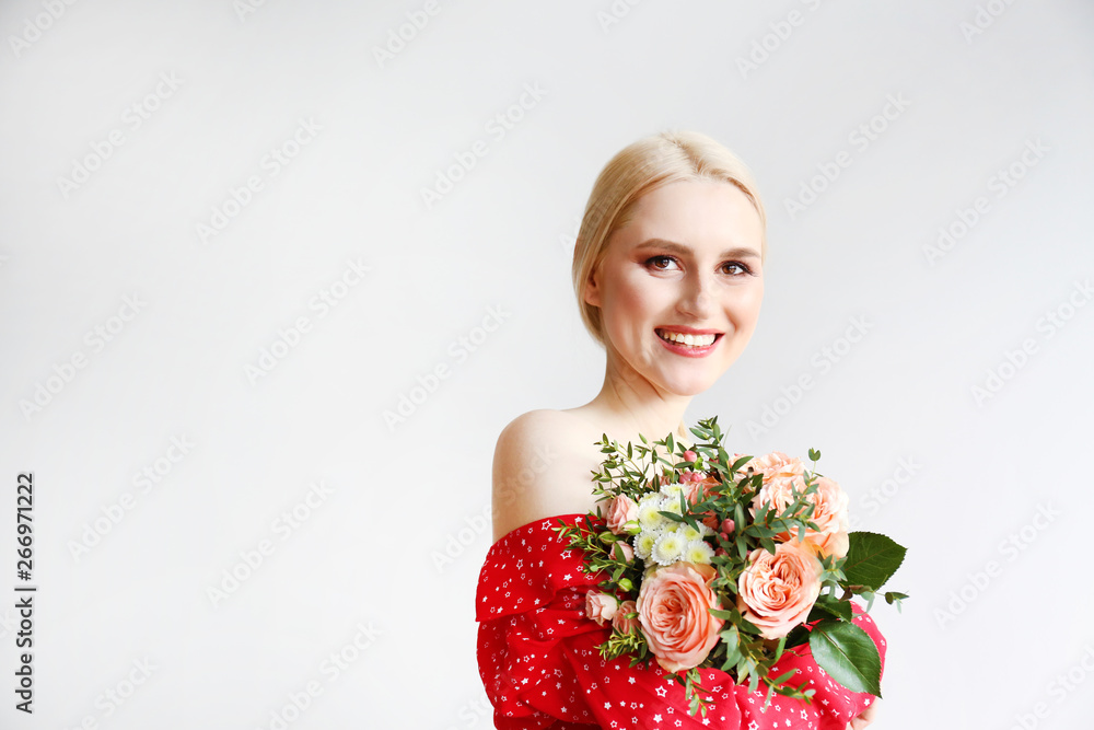 Studio portrait of gorgeous young blonde woman with long straight hair tied in braid wearing red dress and holding bouquet of many tender pale pink roses. Isolated background, copy space, close up. Studio portrait of gorgeous young blonde woman with long straight hair tied in braid wearing red dress and holding bouquet of many tender pale pink roses. Isolated background, copy space, close up.
