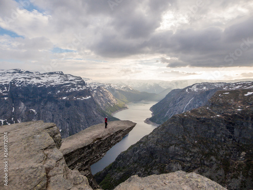 A Girl Wearing Pink Jacket Stands At The Hanging Rock Formation Trolltunga With A View On Ringedalsvatnet Lake Norway Slopes Of The Mountains Are Partially Covered With Snow Freedom And Happiness Stock A Girl Wearing Pink Jacket Stands At The Hanging Rock Formation Trolltunga With A View On Ringedalsvatnet Lake Norway Slopes Of The Mountains Are Partially Covered With Snow Freedom And Happiness Stock