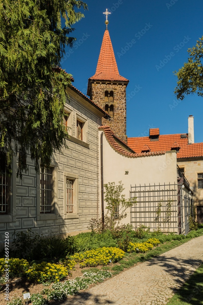 Pruhonice, Czech Republic - April 22 2019: Vertical image of romanesque church of the Holy Virgin Birth with red roof is a part of Pruhonice park area. Sunny spring day with blue sky and flower beds.