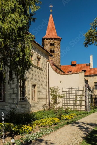 Pruhonice, Czech Republic - April 22 2019: Vertical image of romanesque church of the Holy Virgin Birth with red roof is a part of Pruhonice park area. Sunny spring day with blue sky and flower beds.