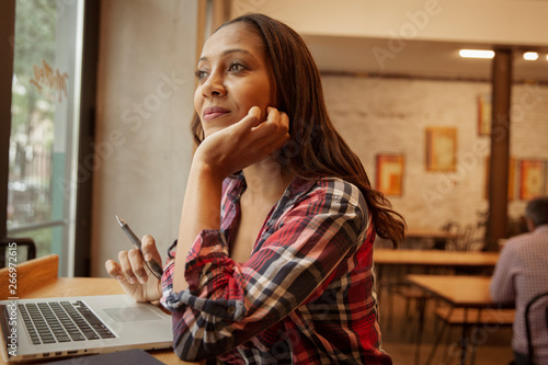 Confident thoughtful businesswoman with laptop computer on table sitting in office cafeteria