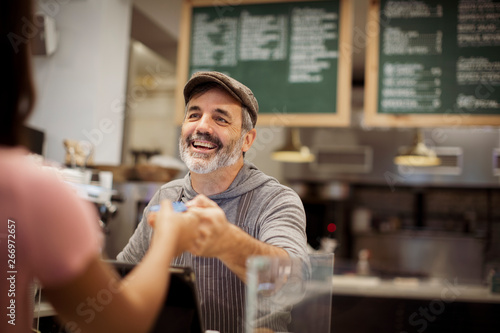 Fotografie Cropped image of female customer giving card payment to owner at counter in cafe