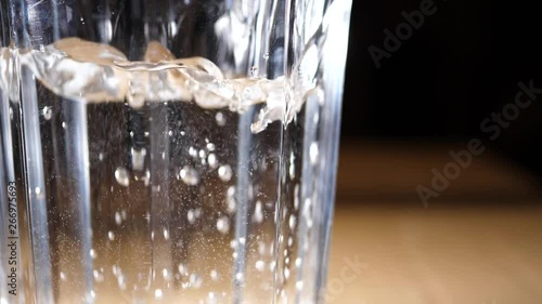 Water pouring in a glass with bubbles. Macro