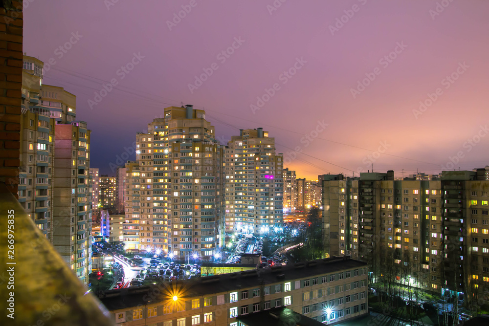 Obraz premium Glowing and sparking lights of night city neighborhood, big tall residential buildings illuminated by light from windows at nights streets, cityscape. Night sleeping area of Saint Petersburg, Russia