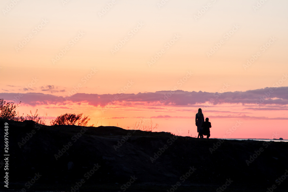 silhouette of man and woman walking on the beach at sunset