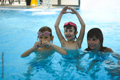 Portrait of children in the pool in spa wellness center. Cute children playing in swimming pool.