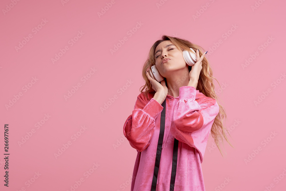 Wireless connection. Portrait of young woman posing isolated over pink background listening fun music with headphones. Wireless connection. Portrait of young woman posing isolated over pink background listening fun music with headphones.