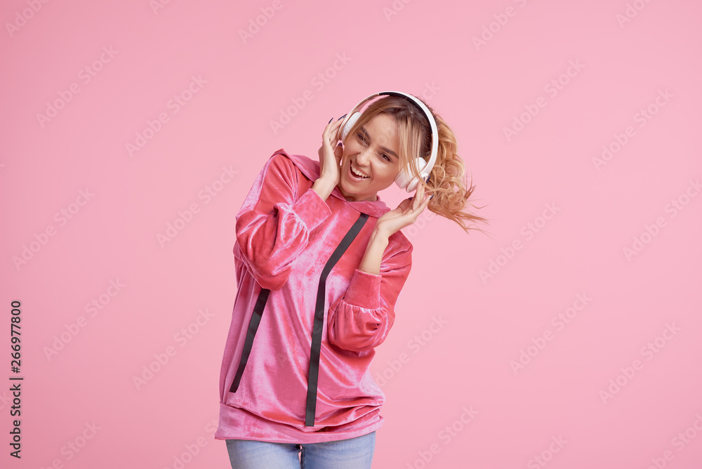 Wireless connection. Portrait of young woman posing isolated over pink background listening fun music with headphones. Wireless connection. Portrait of young woman posing isolated over pink background listening fun music with headphones.
