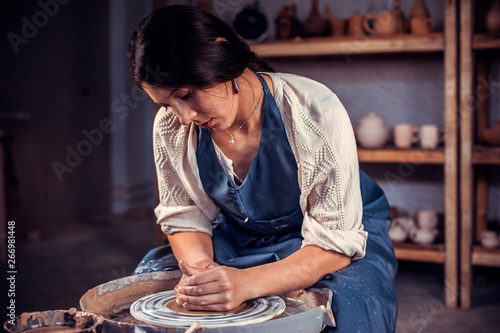 Charming professional potter is working on pottery wheel. Handwork.