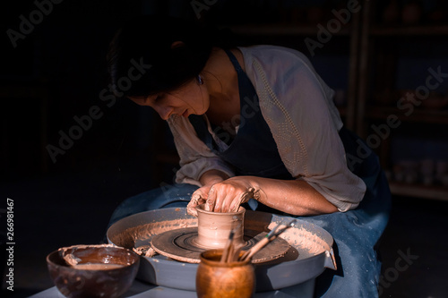 Stylish craftsman master making pottery, sculptor from wet clay on wheel. Craft production.