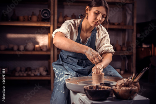 Beautiful ceramist sculptor works with clay on a Potter's wheel and at the table with the tools. Craft production.