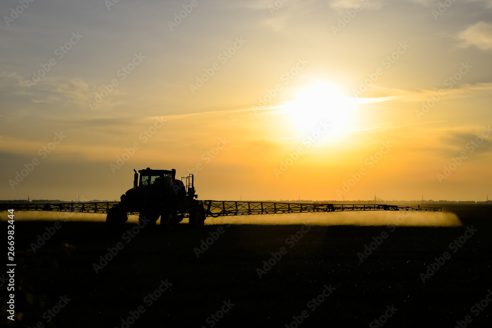 tractor with the help of a sprayer sprays liquid fertilizers on young wheat in the field. tractor with the help of a sprayer sprays liquid fertilizers on young wheat in the field.