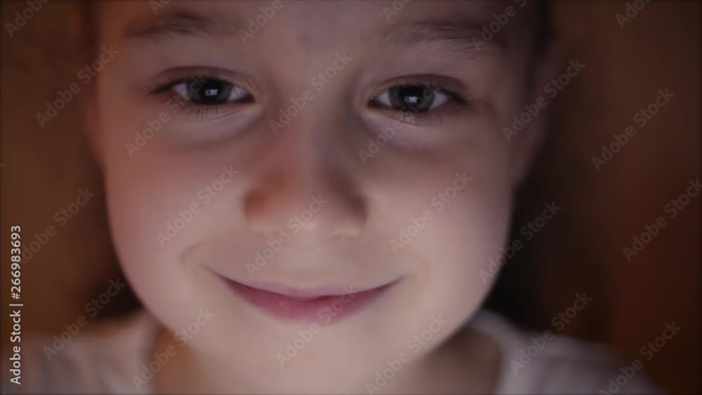 Night Shot of a Cute Caucasian Little Girl Close Up of a Child's Face Viewing a Tablet PC With a Reflection of Pight and Pictures in His Eyes Night Shot of a Cute Caucasian Little Girl Close Up of a Child's Face Viewing a Tablet PC With a Reflection of Pight and Pictures in His Eyes