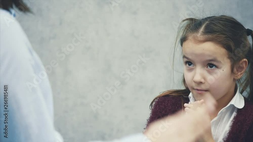 Mom daughter are on a gray background. During this mom is back to the camera and wiggles her daughter's fist, cultivating her.