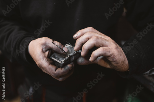 Unrecognizable repairman with dirty hands gluing broken part in workshop photo