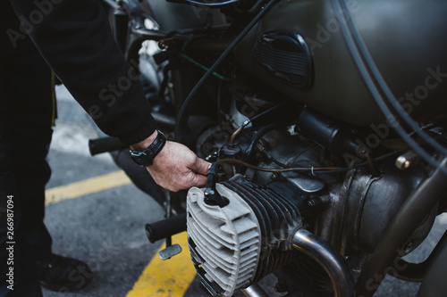 Anonymous male fixing engine of motorbike on parking lot on city street photo