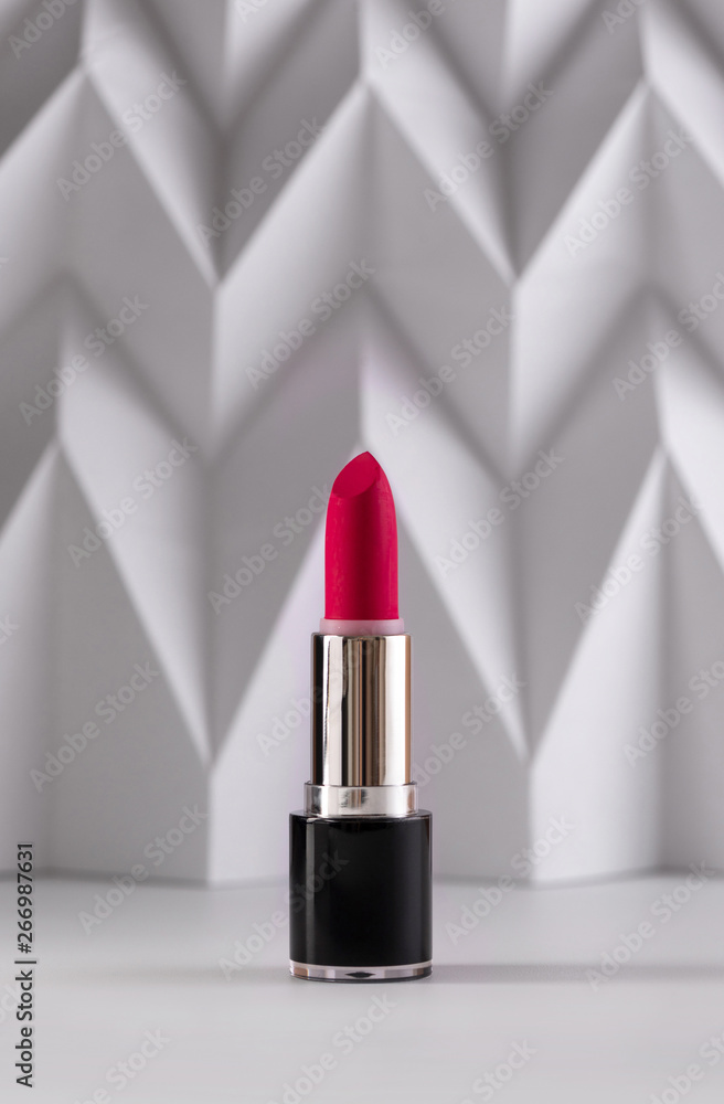 Pink lipstick on raised white chevron. Product and make up contemporary concept Pink lipstick on raised white chevron. Product and make up contemporary concept