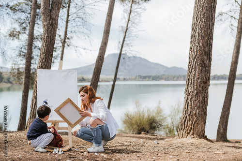 Mother and boy painting near lake photo