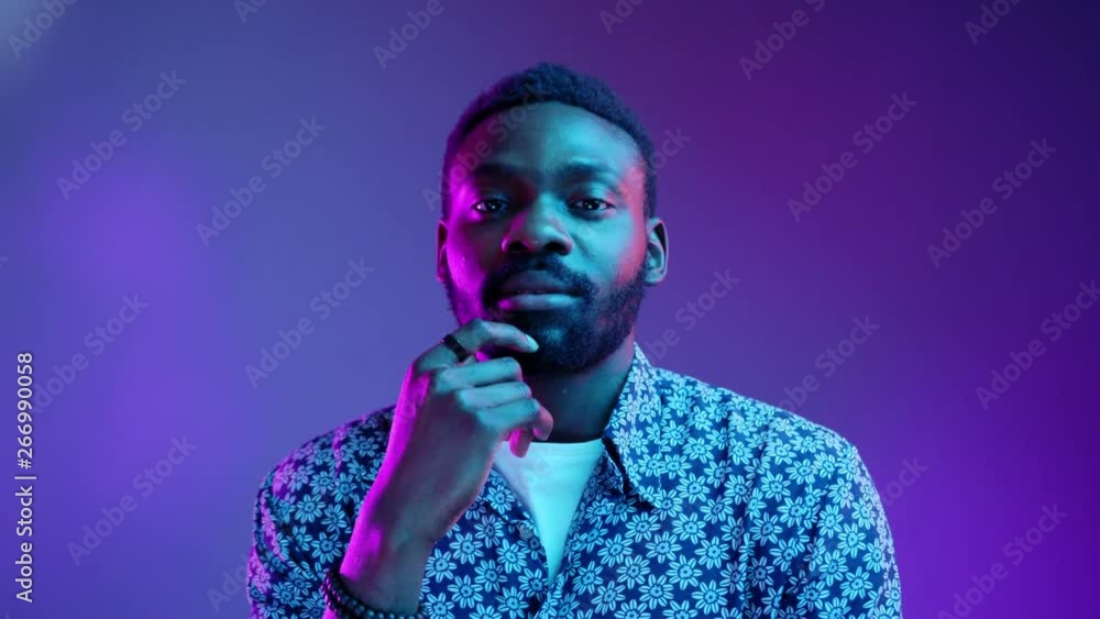 Young thoughtful attractive guy in flowered shirt standing pensively against glowing neon pink light and thinking, has an idea. Facial expression, emotions, feelings. Advertisement concept. Male Young thoughtful attractive guy in flowered shirt standing pensively against glowing neon pink light and thinking, has an idea. Facial expression, emotions, feelings. Advertisement concept. Male