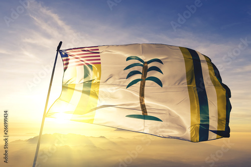 Grand Kru county of Liberia flag waving on the top sunrise mist fog